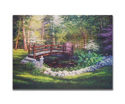 A painting of a garden koi pond, surrounded by stones and crossed by a small bridge. Lily pads grow in the water, and orange and white koi carp swim between them. Printed on a box board.