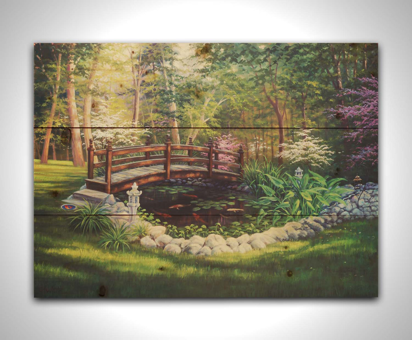 A painting of a garden koi pond, surrounded by stones and crossed by a small bridge. Lily pads grow in the water, and orange and white koi carp swim between them. Printed on a wood pallet.