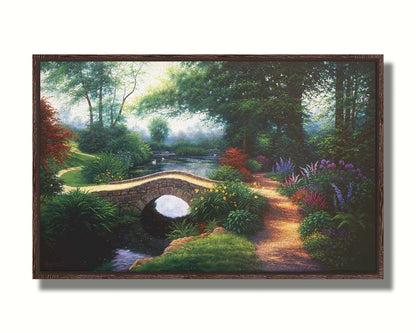 A painting of a serene garden path winding between flowers and trees. A stone bridge crosses over a tranquil pond inhabited by graceful swans. Printed on canvas in a float frame.