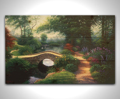 A painting of a serene garden path winding between flowers and trees. A stone bridge crosses over a tranquil pond inhabited by graceful swans. Printed on a wood pallet.