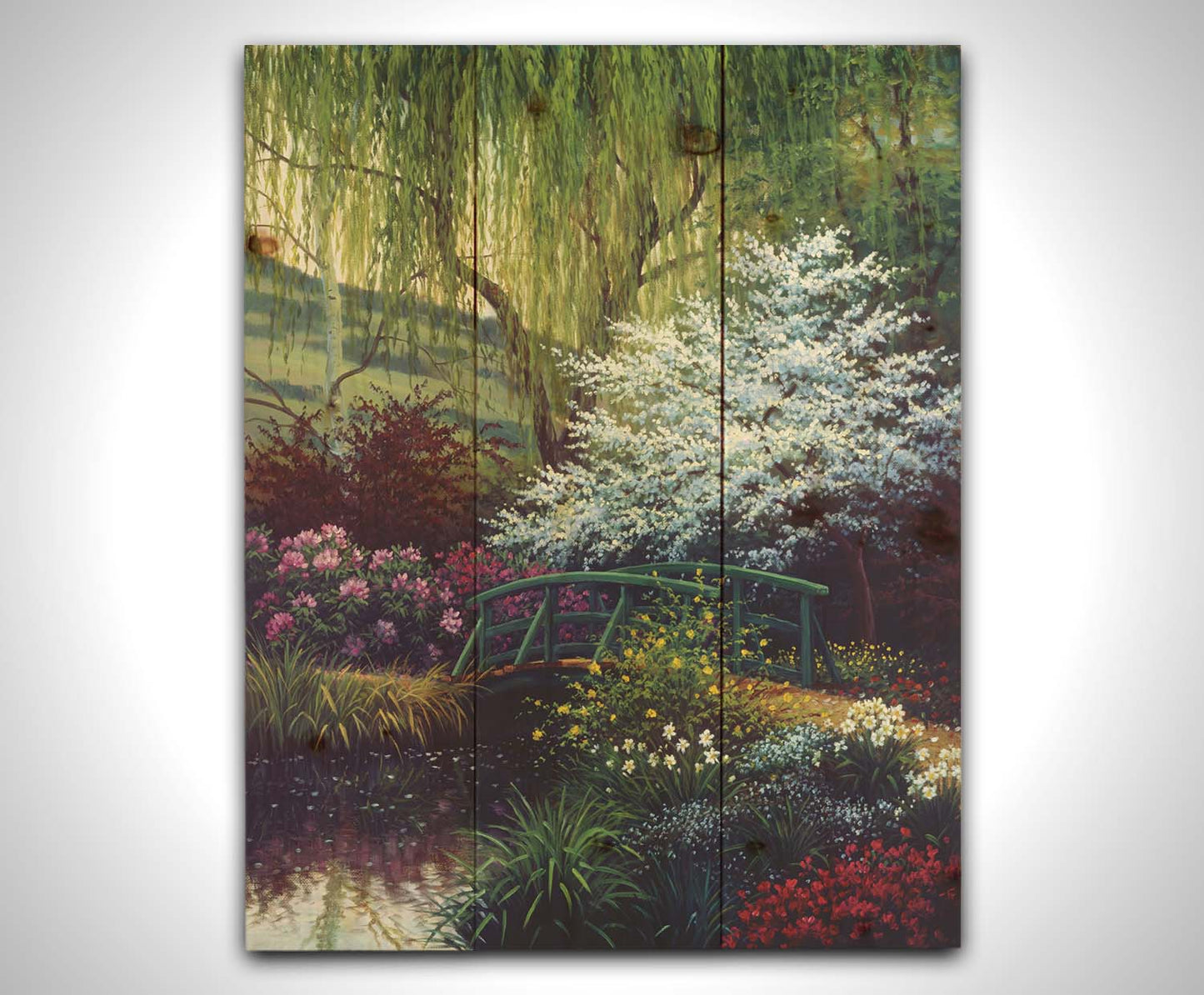 A painting of Claude Monet’s iconic water lily pond in Giverny, France, featuring a small bridge over the canal that brings water into the pond. It is surrounded by willow trees, trees with white and red blossoms, and a variety of flowers. Printed on a wood pallet.