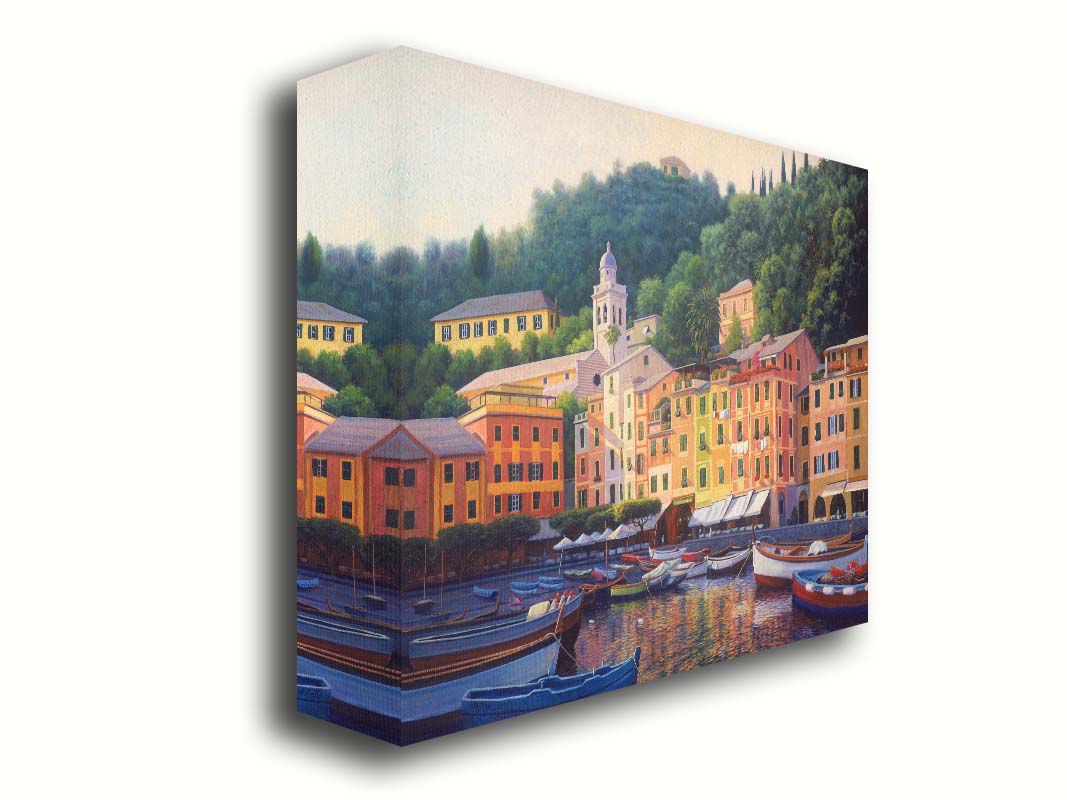 A painting of the colorful fishing town of Portofino. Many small boats are docked in the waters in the foreground, and the steep hills in the background are lush with trees. Printed on canvas.