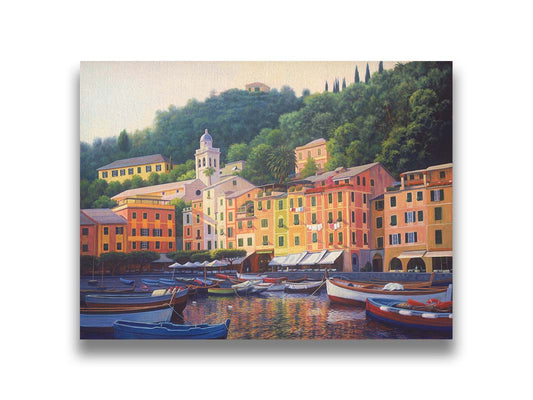 A painting of the colorful fishing town of Portofino. Many small boats are docked in the waters in the foreground, and the steep hills in the background are lush with trees. Printed on canvas.