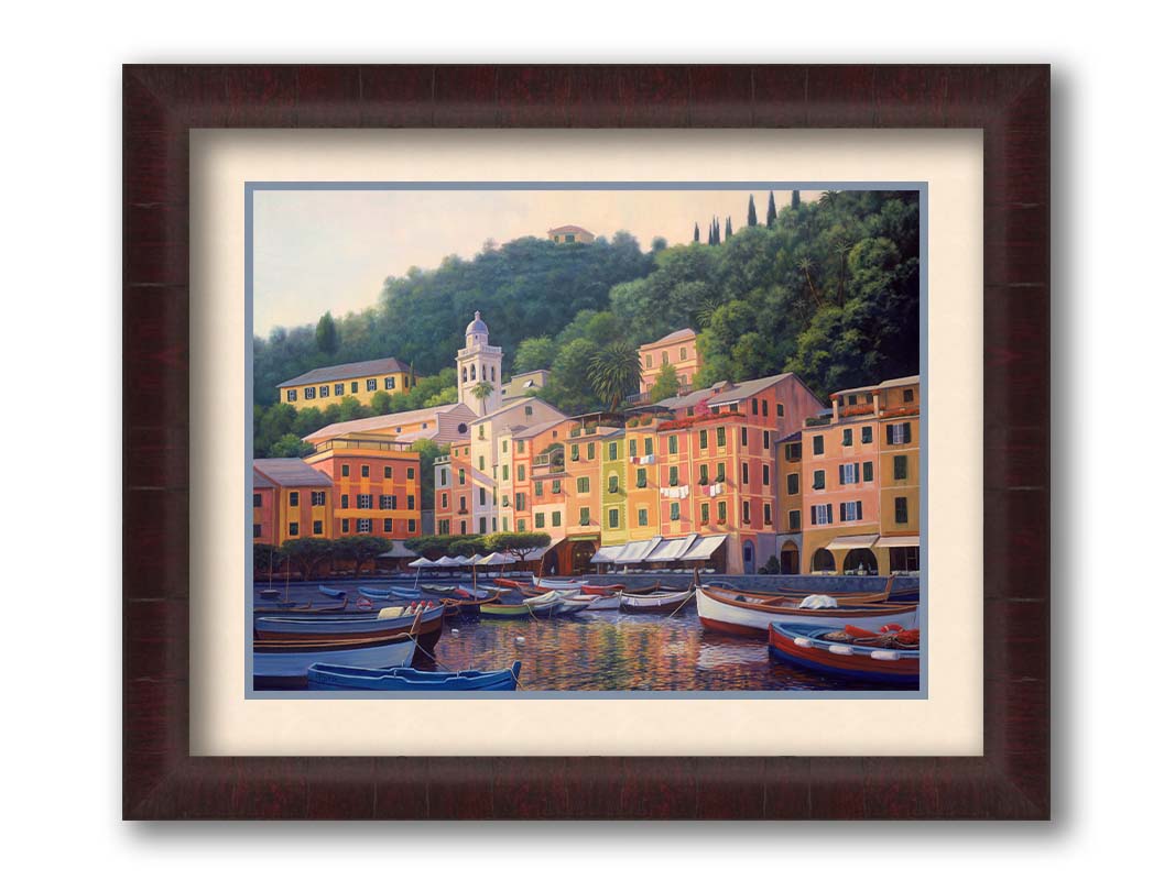 A painting of the colorful fishing town of Portofino. Many small boats are docked in the waters in the foreground, and the steep hills in the background are lush with trees. Printed on paper, matted, and framed.