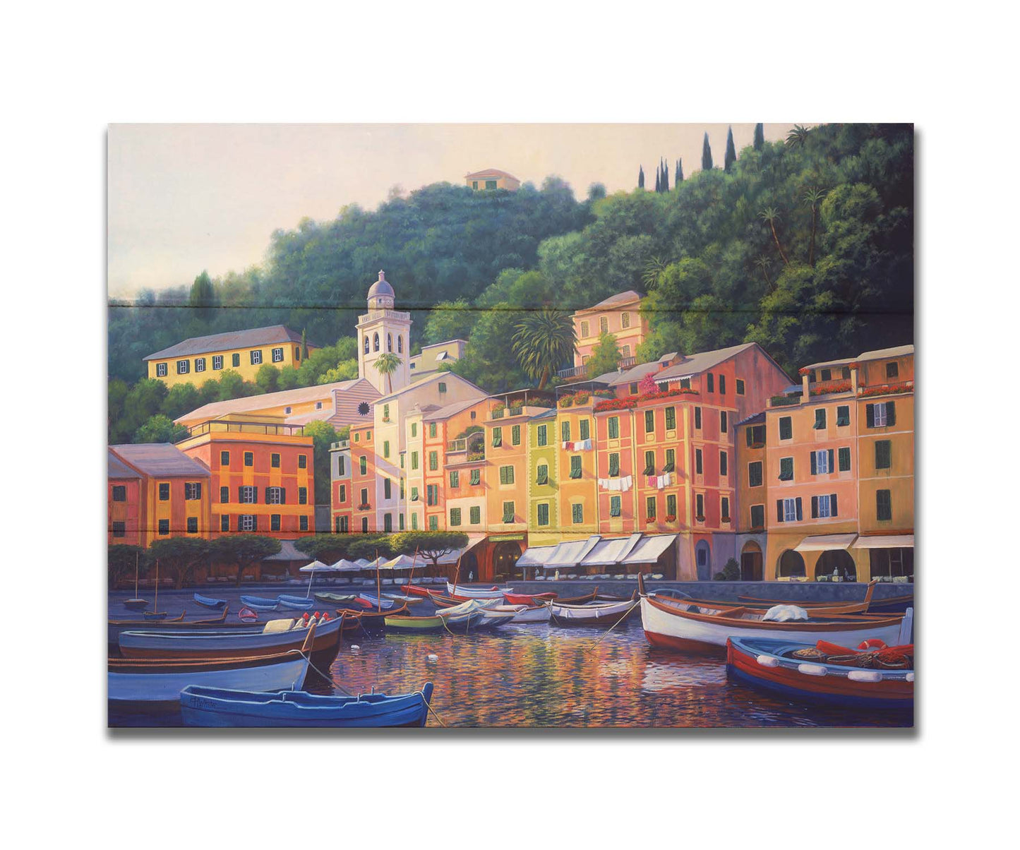 A painting of the colorful fishing town of Portofino. Many small boats are docked in the waters in the foreground, and the steep hills in the background are lush with trees. Printed on a box board.