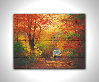 A painting of a road through the fall woods, with colorful leaves. A Schwan's food delivery truck drives away down the road. Printed on a wood pallet.