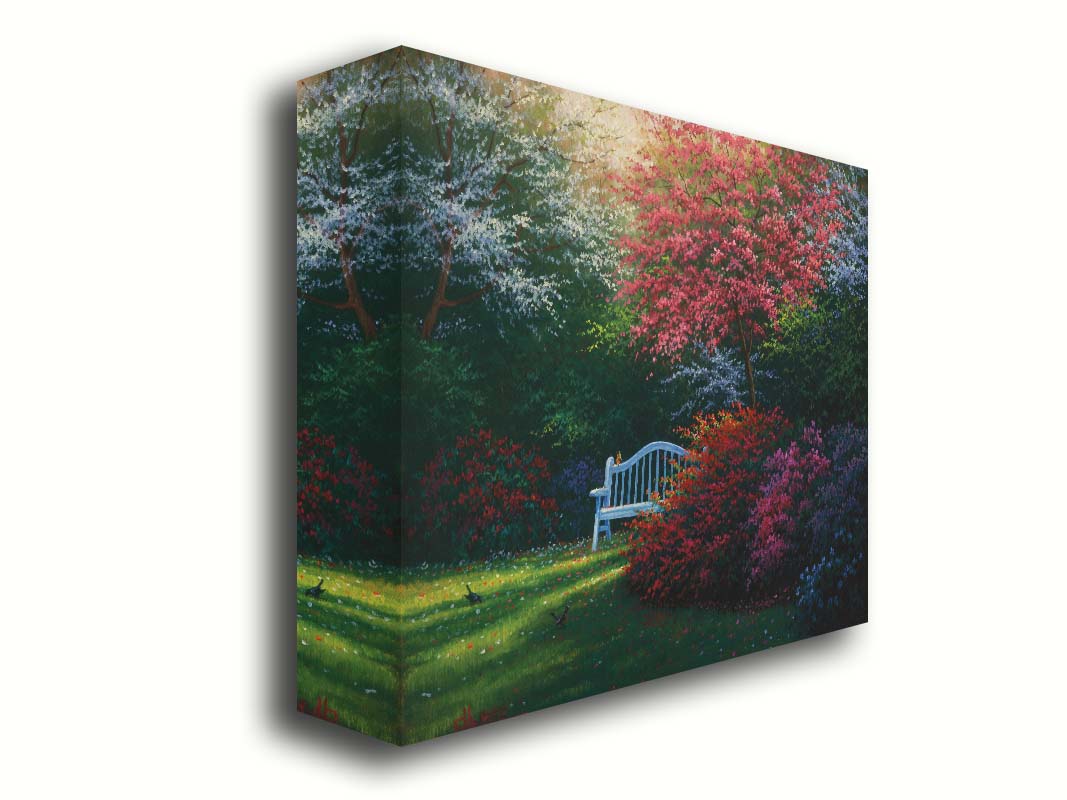 A painting of a garden bench peeking between vibrant flower bushes in red, pink, purple, and blue, all beneath pink and white blossoming trees. Printed on canvas.