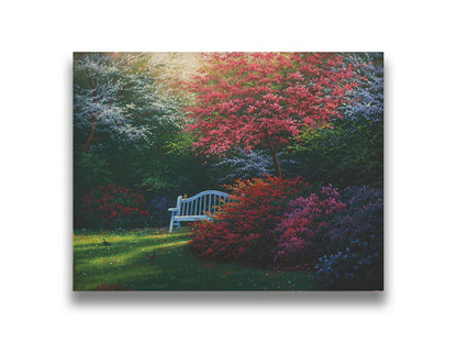 A painting of a garden bench peeking between vibrant flower bushes in red, pink, purple, and blue, all beneath pink and white blossoming trees. Printed on canvas.