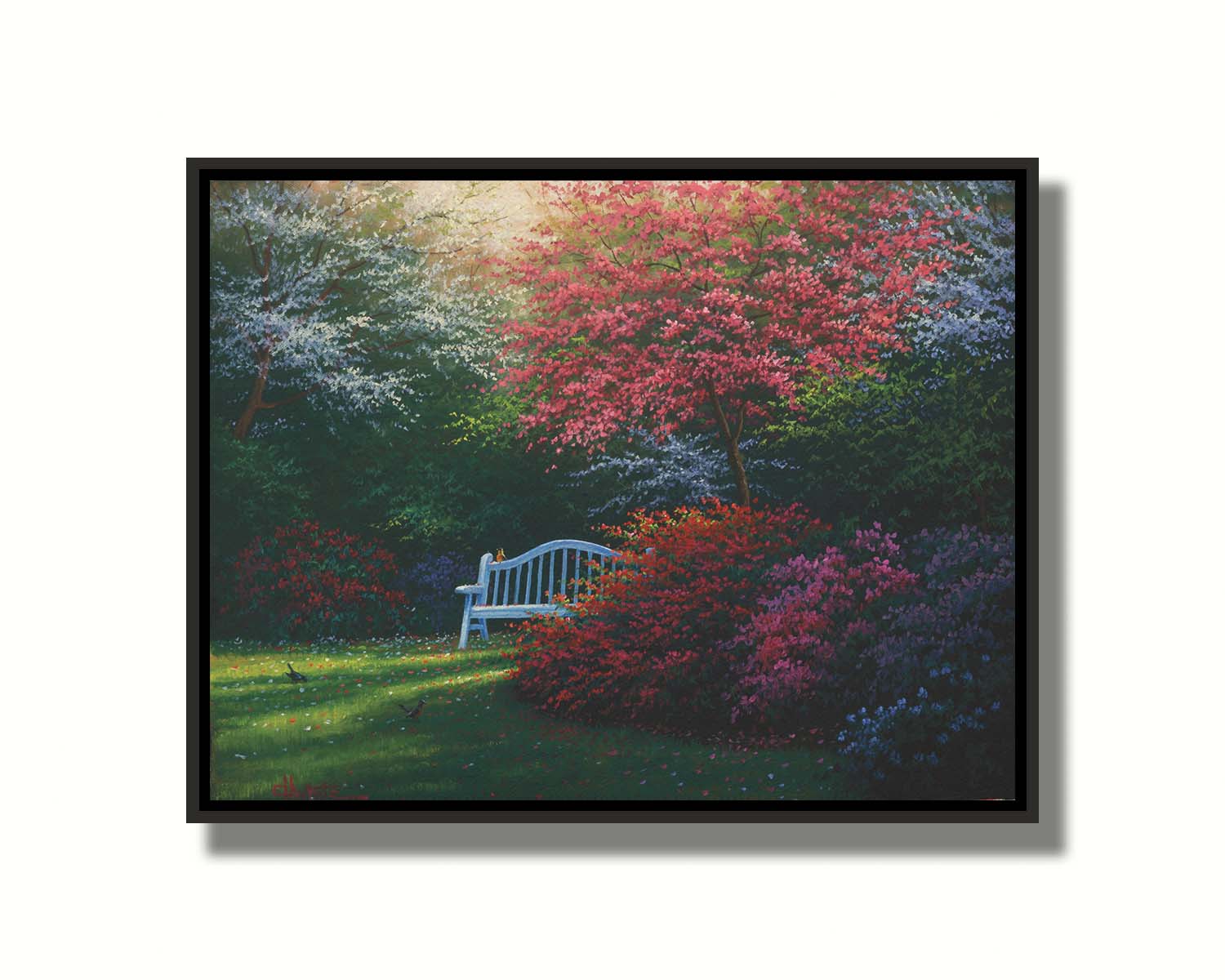 A painting of a garden bench peeking between vibrant flower bushes in red, pink, purple, and blue, all beneath pink and white blossoming trees. Printed on canvas in a float frame.