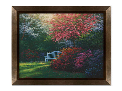 A painting of a garden bench peeking between vibrant flower bushes in red, pink, purple, and blue, all beneath pink and white blossoming trees. Printed on canvas and framed.