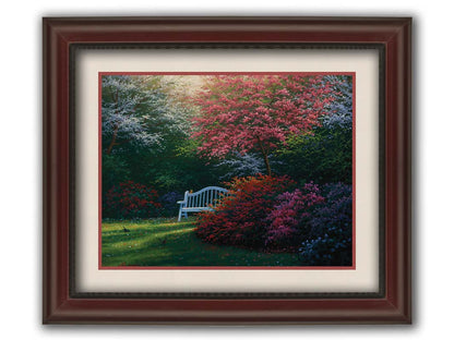 A painting of a garden bench peeking between vibrant flower bushes in red, pink, purple, and blue, all beneath pink and white blossoming trees. Printed on paper, matted, and framed.