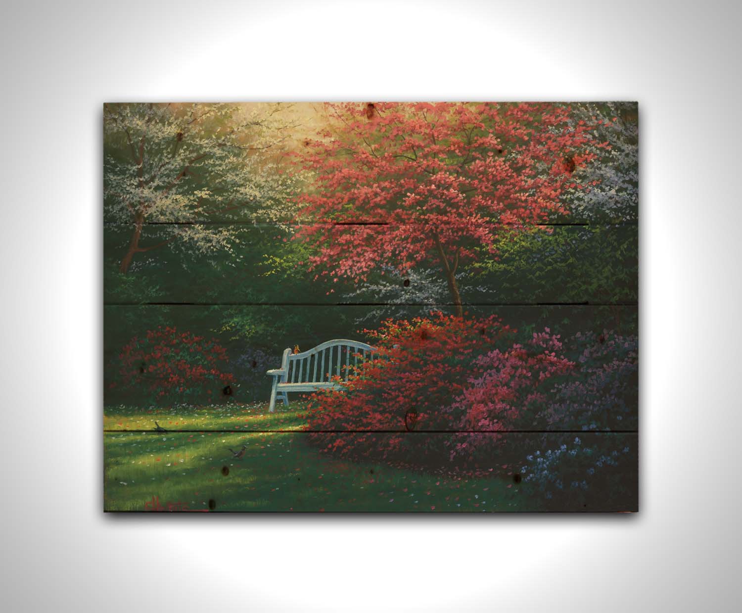 A painting of a garden bench peeking between vibrant flower bushes in red, pink, purple, and blue, all beneath pink and white blossoming trees. Printed on a wood pallet.