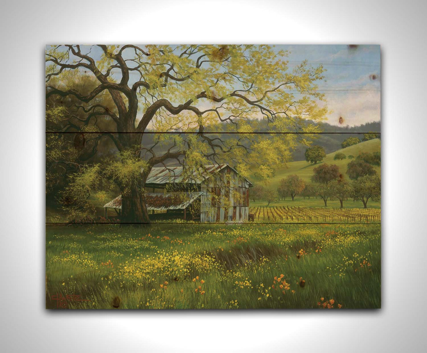 A painting of a green spring scene of an old barn nestled between a vineyard and a flowery meadow, with forested hills in the distance. Printed on a wood pallet.