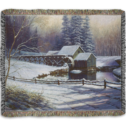 Woven throw blanket with a winter landscape design featuring a cabin and snowy trees.