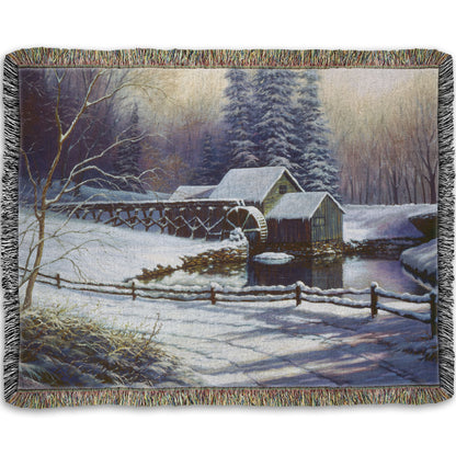 Woven throw blanket with a winter landscape design featuring a cabin and snowy trees.
