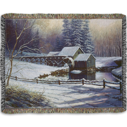 Woven throw blanket with a winter landscape design featuring a cabin and snowy trees.