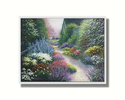 A painting of a gravel path through a garden with dense, colorful growths of flowers. The path and garden borders lead to cozy cottages. Printed on canvas in a float frame.