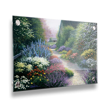 A painting of a gravel path through a garden with dense, colorful growths of flowers. The path and garden borders lead to cozy cottages. Printed on acrylic.