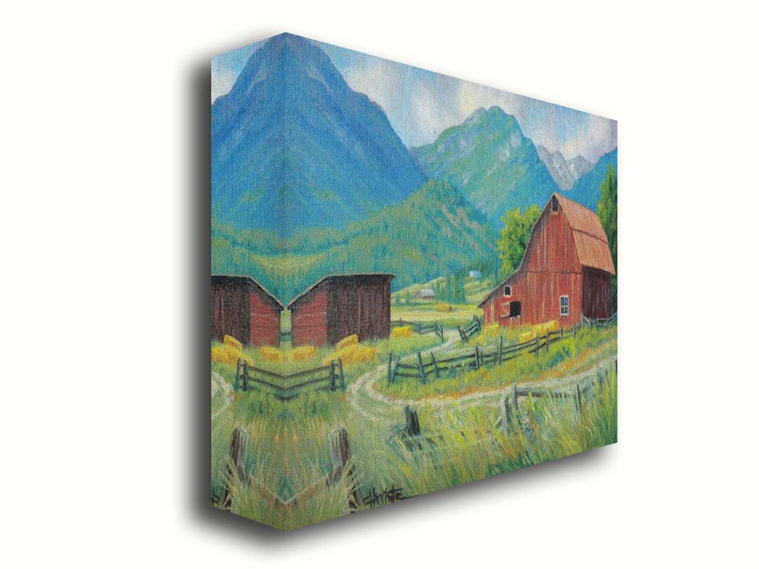 A painting of a red barn and shed surrounded by green pastures. Forested mountains stand tall in the background. Printed on canvas,