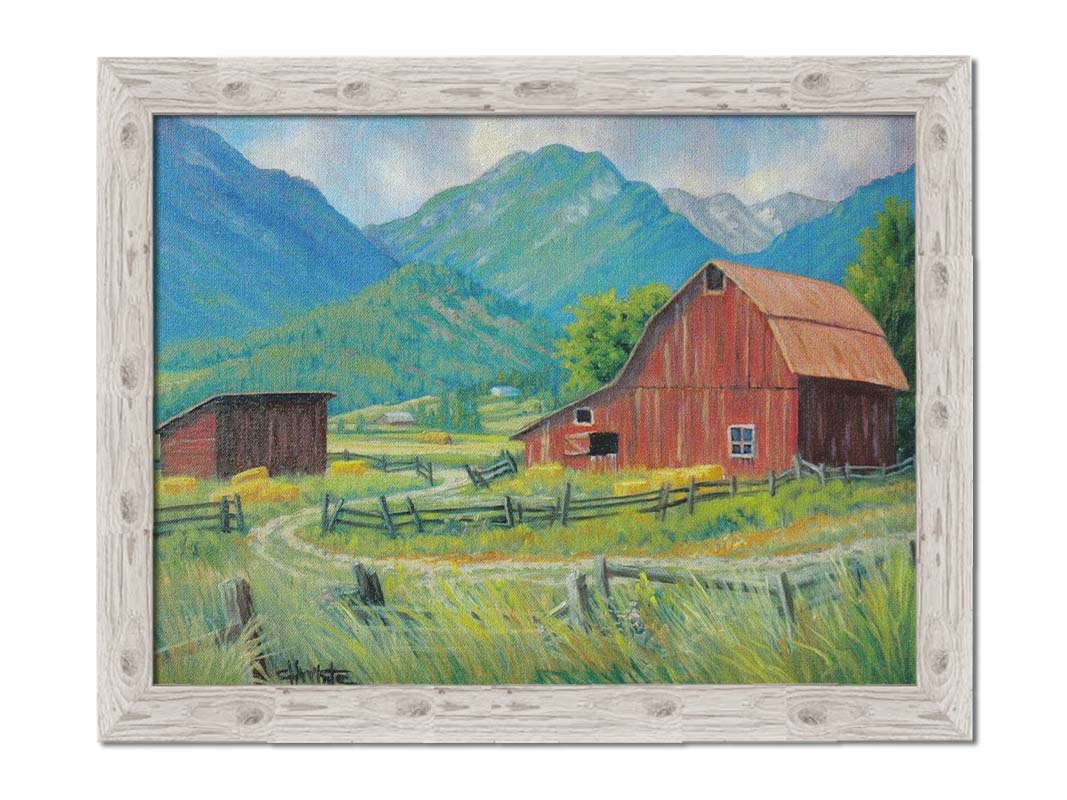 A painting of a red barn and shed surrounded by green pastures. Forested mountains stand tall in the background. Printed on canvas and framed.