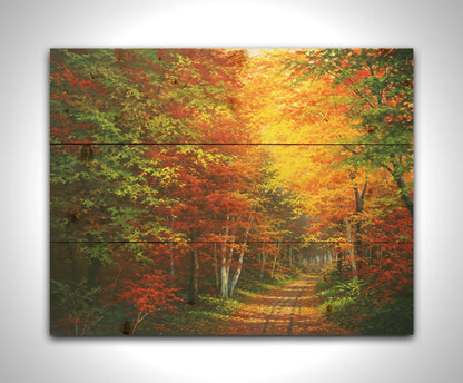 A painting of a leaf-strewn road through a forest, with light filtering through the branches to highlight the golden hues of fall. Printed on a wood pallet.