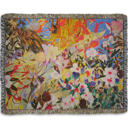 Woven throw blanket designed with an abstract flower garden utilizing vibrant and bold flat color. Flowers of all shapes, sizes, and colors can be seen against a baby blue sky.