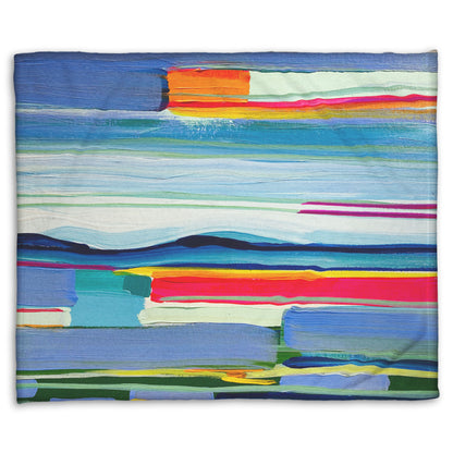 A woven throw blanket designed with an abstract painting of colorful horizontal lines. The blue and orange are reminiscent of a sun setting over the sea. 