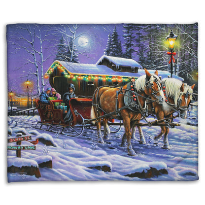 A coral fleece blanket printed with a painting of people on a horse-drawn sleigh ride around a lake during Christmas.