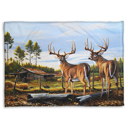 A coral fleece blanket designed with a painting of a farm landscape, featuring two deer in the foreground. Fields, buildings, hay bales, and farming equipment can be seen beyond the fence, and fallen leaves cover the ground. 