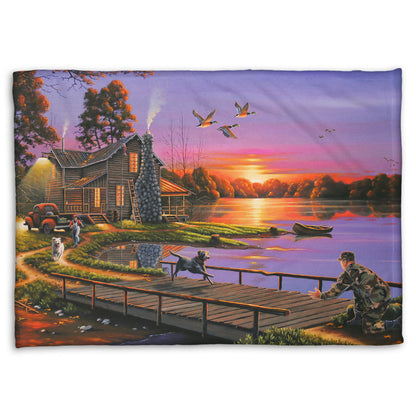 A coral fleece blanket designed with a painting of a soldier returning home to his house on the lake, being greeted by his family and dogs. Geese fly overhead into the sunset. 