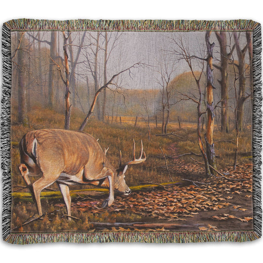 A woven throw blanket designed with a painting of deer approaching each other in the woods. The two bucks are about to fight, as is evident by their body language.