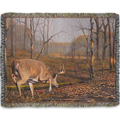 A woven throw blanket designed with a painting of deer approaching each other in the woods. The two bucks are about to fight, as is evident by their body language.