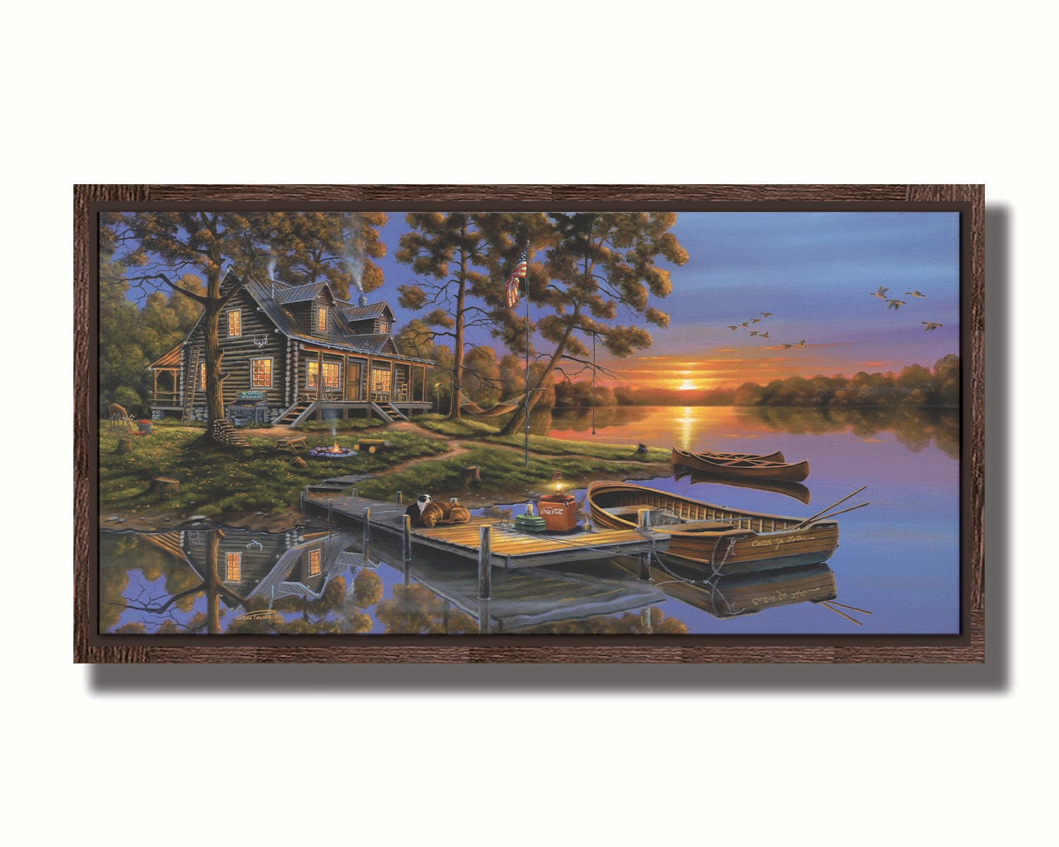 A painting of an American lakeside cabin at sunset, with boats on the water and geese overhead. Printed on canvas in a float frame.