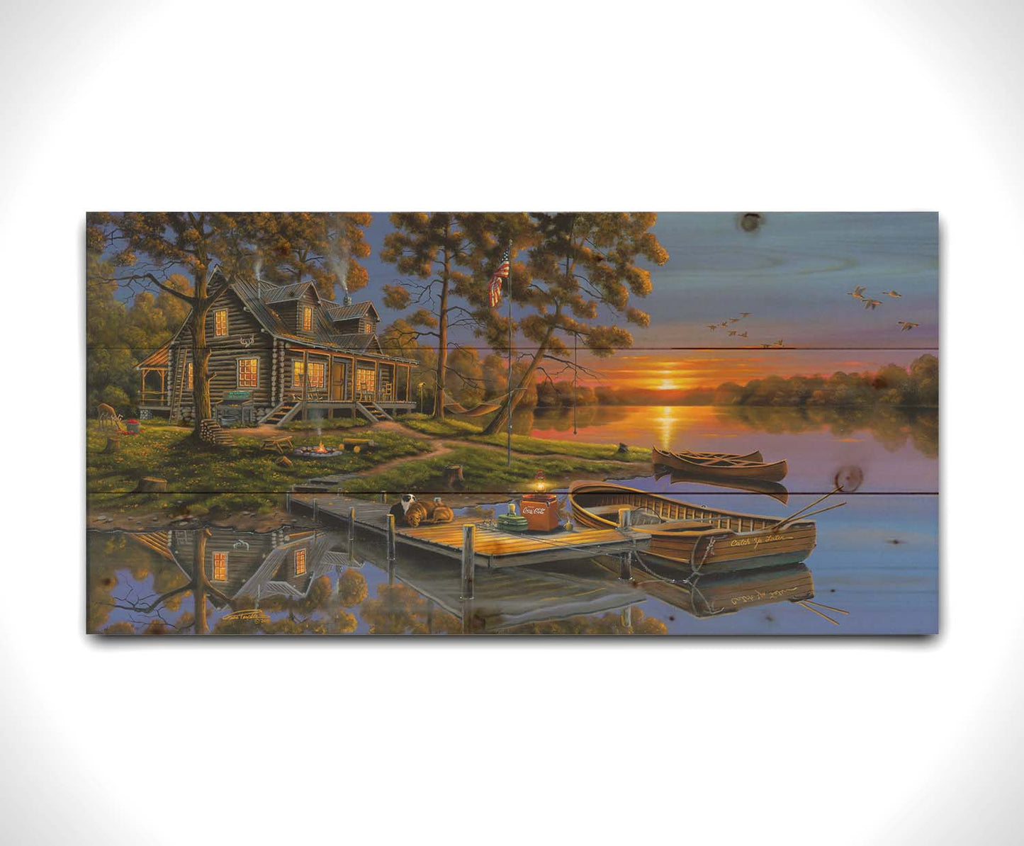 A painting of an American lakeside cabin at sunset, with boats on the water and geese overhead. Printed on a wood pallet.