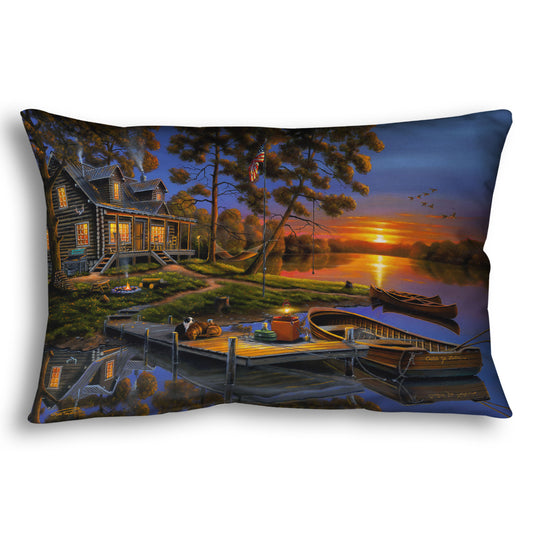 A throw pillow designed with a painting of an American lakeside cabin at sunset, with boats on the water and geese overhead.
