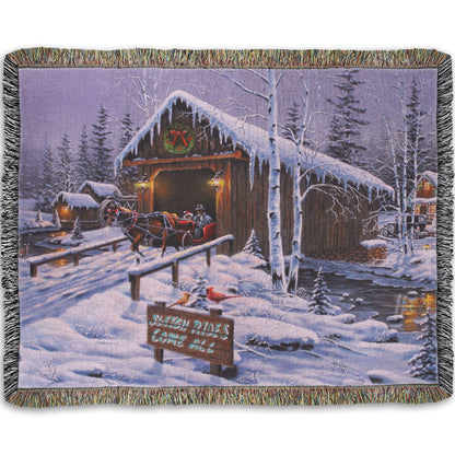 A woven throw blanket designed with a painting of people going for a ride in a horse-drawn sleigh on a snowy night.