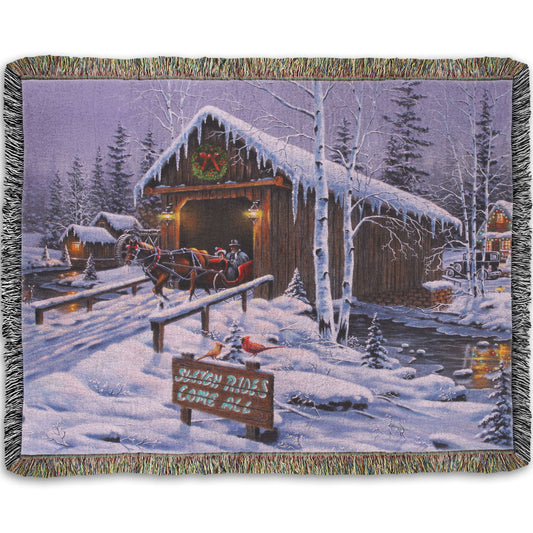 A woven throw blanket designed with a painting of people going for a ride in a horse-drawn sleigh on a snowy night.