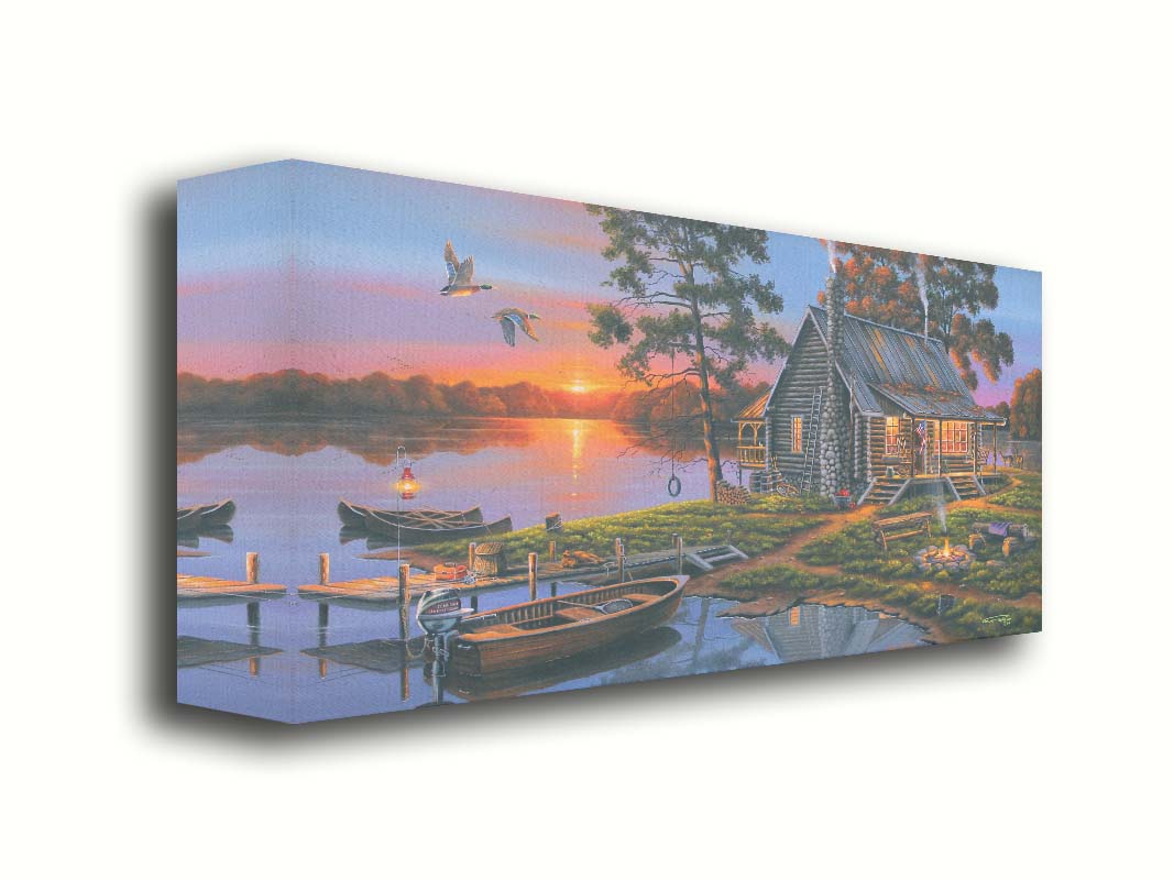 A painting of a lakeside cabin in a deciduous forest of the United States. The sunset is reflected by the water, where several small boats are docked. A lit campfire, deer, geese, and dog bring extra life to the scene. Printed on canvas.