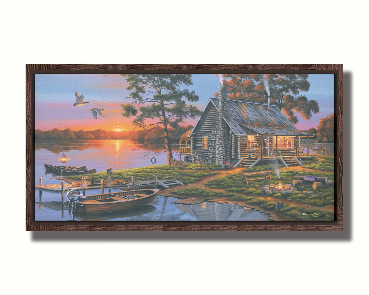 A painting of a lakeside cabin in a deciduous forest of the United States. The sunset is reflected by the water, where several small boats are docked. A lit campfire, deer, geese, and dog bring extra life to the scene. Printed on canvas in a float frame.