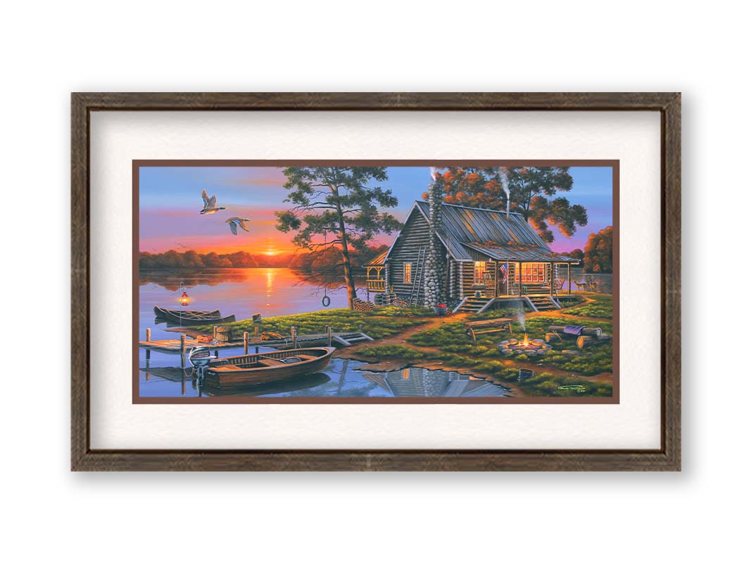 A painting of a lakeside cabin in a deciduous forest of the United States. The sunset is reflected by the water, where several small boats are docked. A lit campfire, deer, geese, and dog bring extra life to the scene. Printed on paper, matted, and framed.