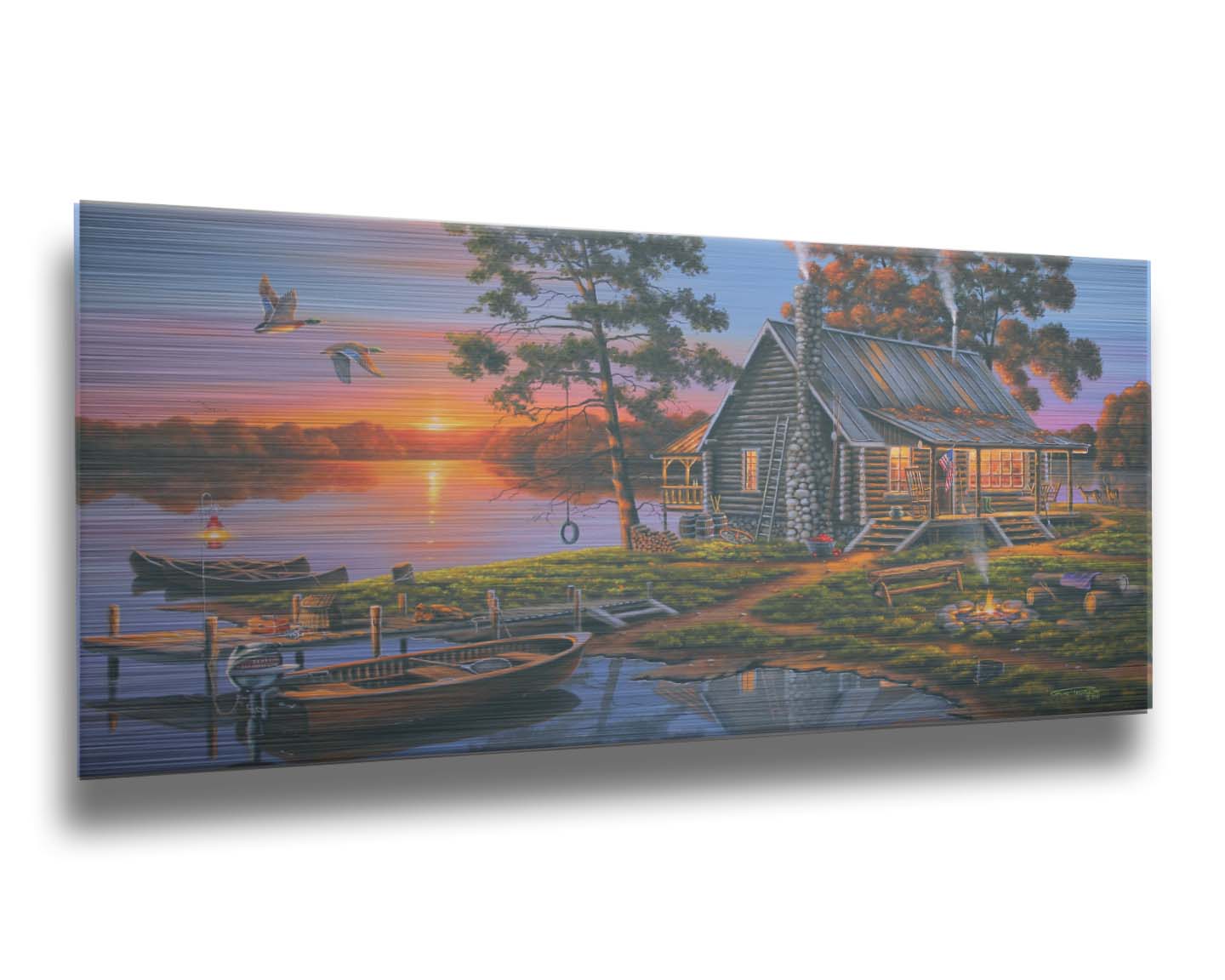 A painting of a lakeside cabin in a deciduous forest of the United States. The sunset is reflected by the water, where several small boats are docked. A lit campfire, deer, geese, and dog bring extra life to the scene. Printed on metal.