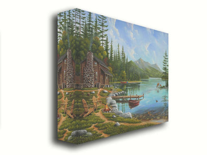 A painting of a lakeside cabin on a sunny day. Boats can be seen on the water, which reflects the mountains in the distance. Deer drink from the lake, where ducks are swimming. Wood chairs surround a small campfire on the shore nearby. Printed on canvas.