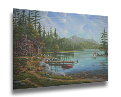 A painting of a lakeside cabin on a sunny day. Boats can be seen on the water, which reflects the mountains in the distance. Deer drink from the lake, where ducks are swimming. Wood chairs surround a small campfire on the shore nearby. Printed on metal.