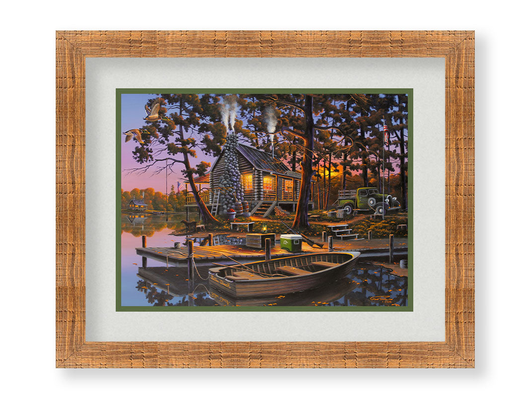 A painting of a lakeside log cabin hunting lodge at sunset. A rowboat is tied to the nearby dock, where shotguns are leaned against a cooler. Printed on paper, matted, and framed.