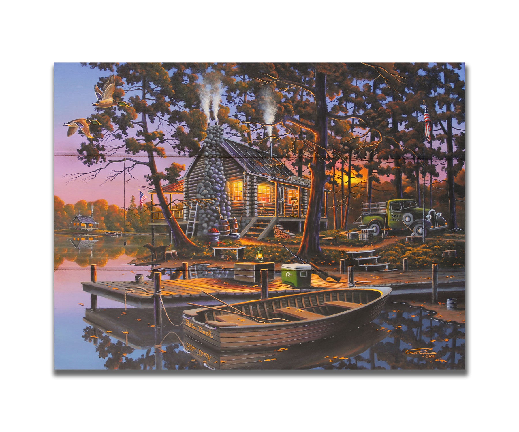 A painting of a lakeside log cabin hunting lodge at sunset. A rowboat is tied to the nearby dock, where shotguns are leaned against a cooler. Printed on a box board.