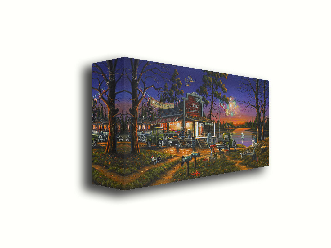 A landscape painting of a lakeside café at sunset, overlooking a colorful fireworks display over the lake on Veterans Day. People sit in the grass watching the excitement. Printed on canvas.