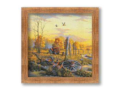 A landscape painting of autumn trees and a field. A tractor, a broken wheel, and a broken fence post add extra character to the scene. Pheasants sit in the foreground and ducks fly overhead. The sky and field are as golden yellow as the trees, in the morning light. Printed on canvas and framed.