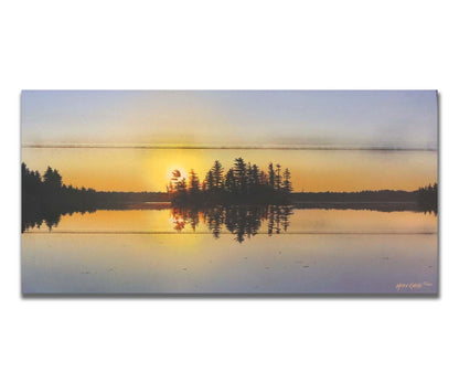 A painting of a low sun reflecting off the waters of a lake, surrounded by forest. Printed on a box board.