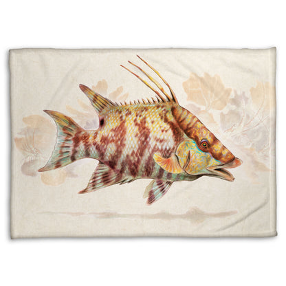 A fleece throw blanket designed with a painting of a hogfish against a soft coral background, all isolated in a warm neutral space.