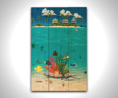 A vibrant painting of an island ocean scene. Three homes sit on an island in the background, while the foreground shows tangs, angelfish, dolphins, starfish, sea turtles, and more beneath the waves alongside corals. Printed on a wood pallet.